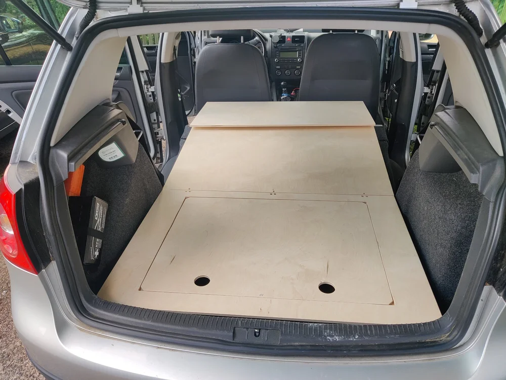 Ausgeklappte Liegefläche der Rost Box aus Birkenholz im VW Golf, über den umgeklappten Rücksitzen